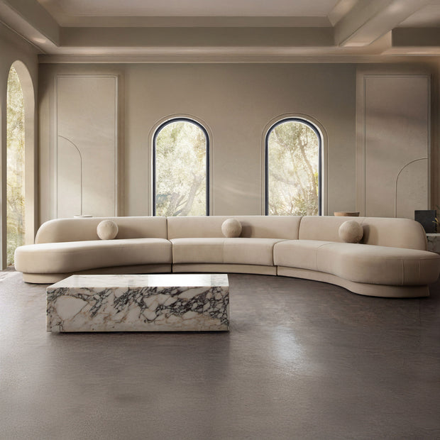 Modern beige sofa in a stylish room with arched windows and a marble coffee table.