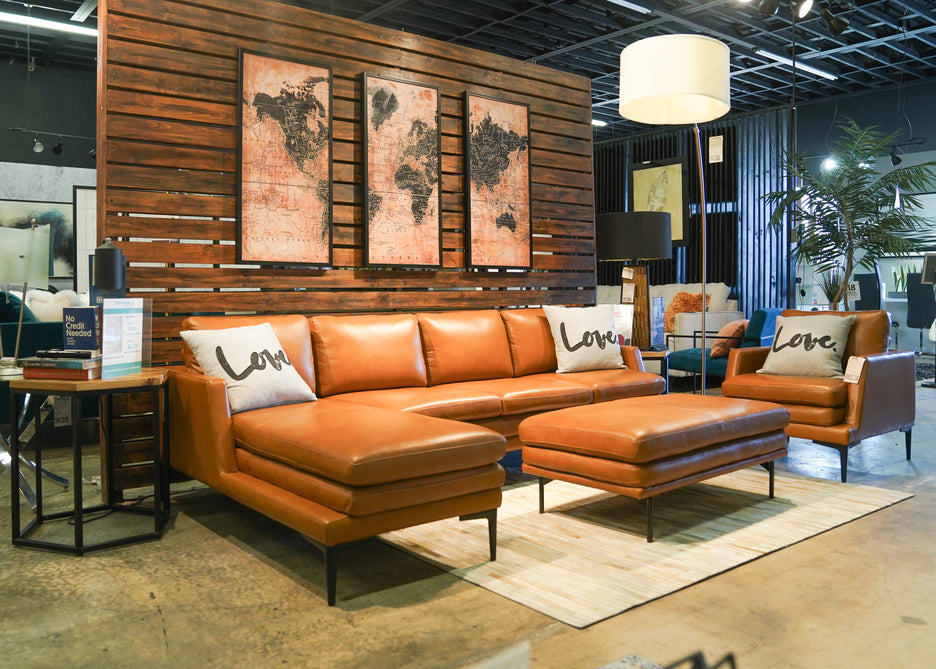 Tan color sectional with ottoman and chair in Caravana Furniture showroom.