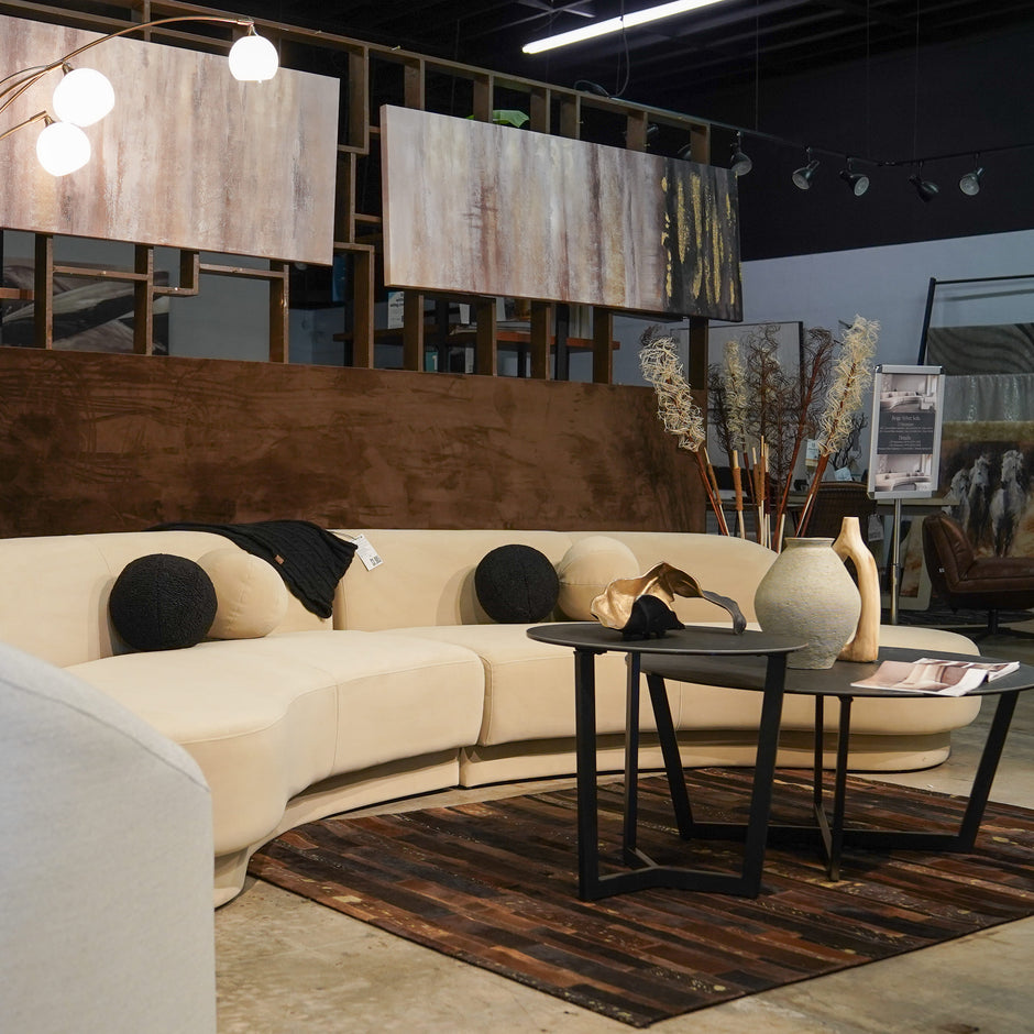 Modern cream color velvet sectional with black coffee tables in Caravana Furniture Showroom