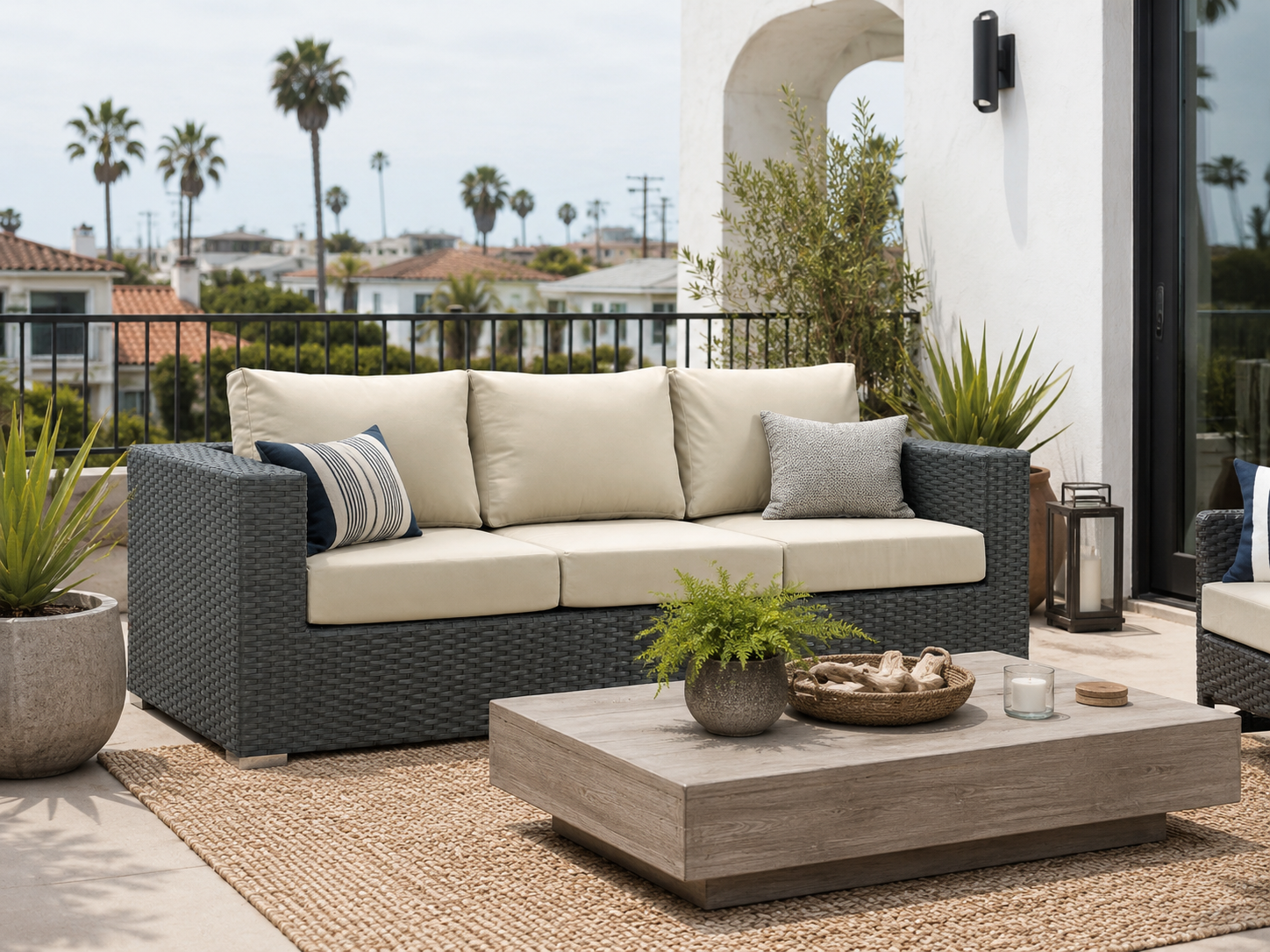 All-weather resin wicker sofa with cream cushions styled on a coastal patio