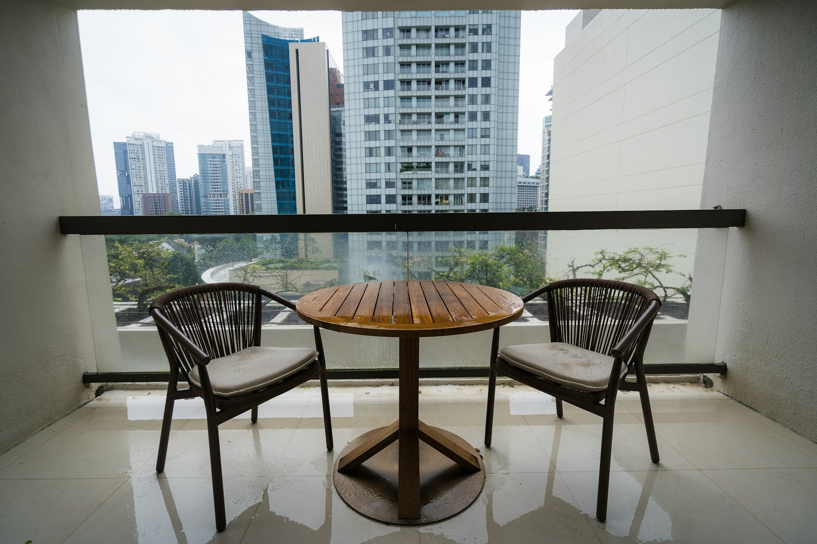 Small balcony with a round bistro table and two chairs angled into the corner