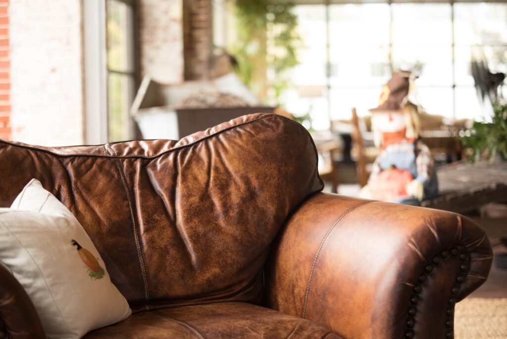 Brown leather couch with wrinkles and white pillow