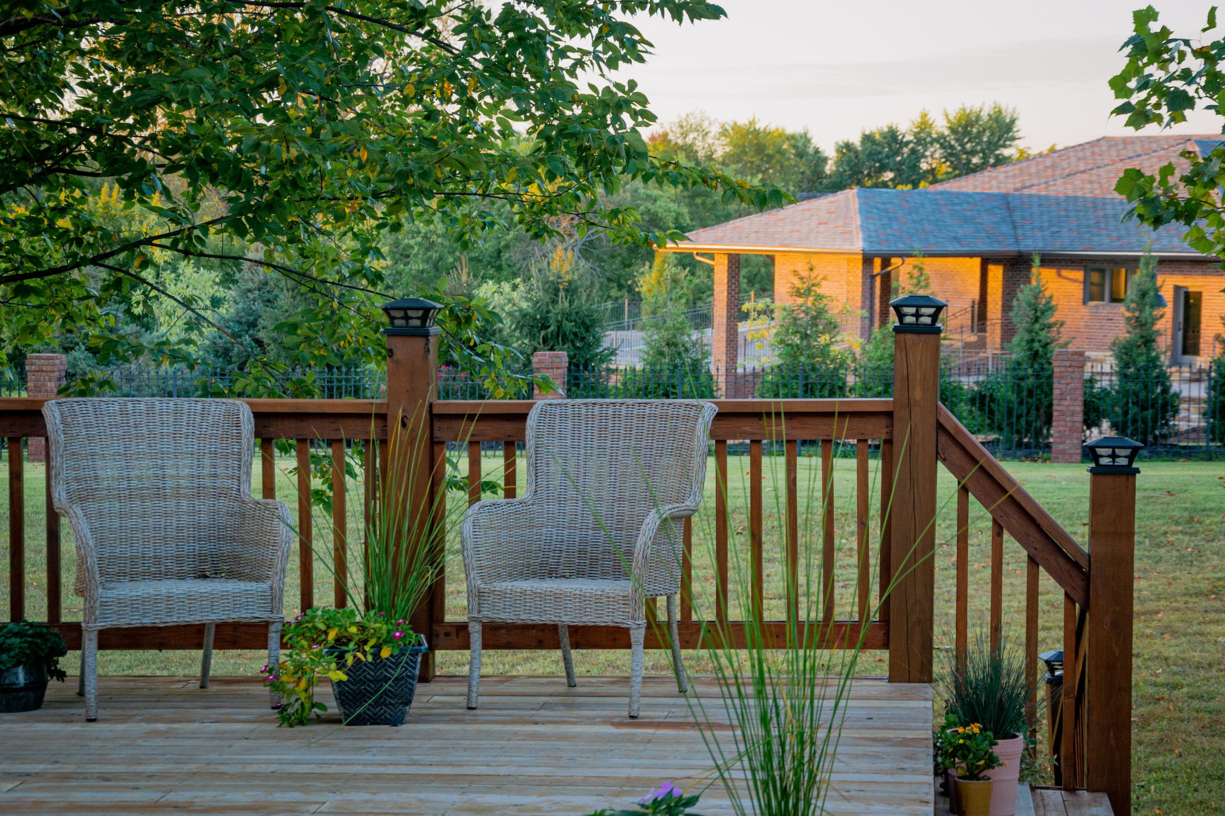 Two wicker chairs on a small deck decorated with plants